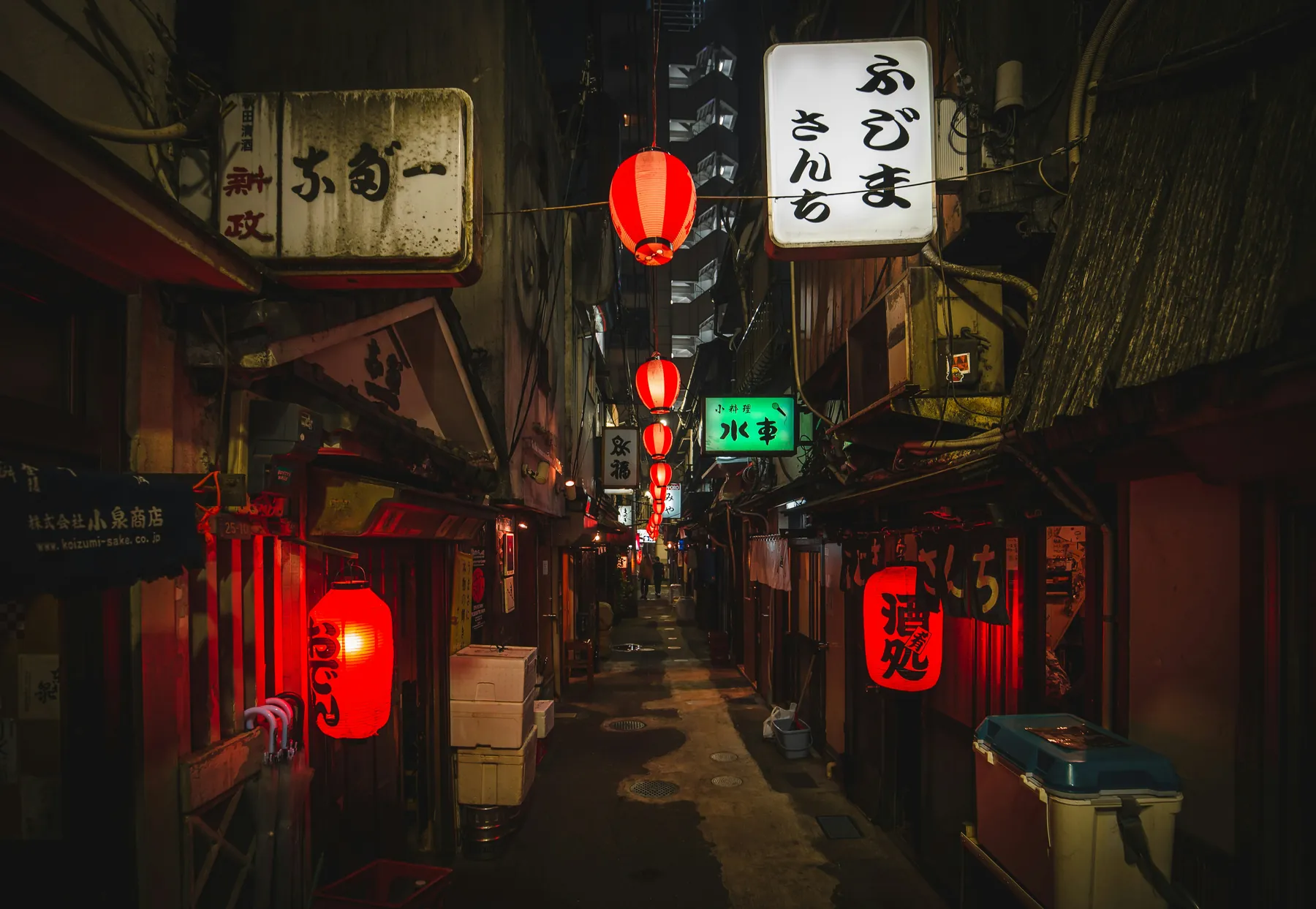 A narrow Tokyo alley at night lined with glowing red lanterns and illuminated signs